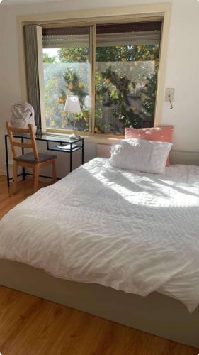 a bedroom with a bed and a chair and a window at Homestay Lemon room close to station, gym, airport in Melbourne