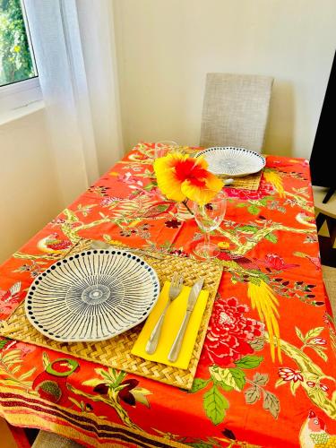 a table with a red table cloth with plates and napkins at Lakaz Kreol Soupir Tourist Résidence in Rodrigues Island