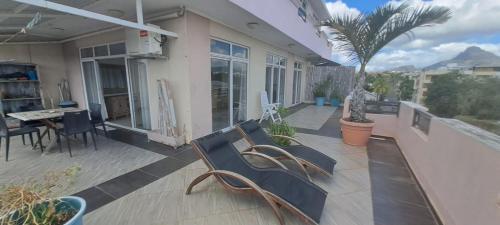 a patio with chairs and a table and a palm tree at LOFT central avec terrasse in Flic-en-Flac