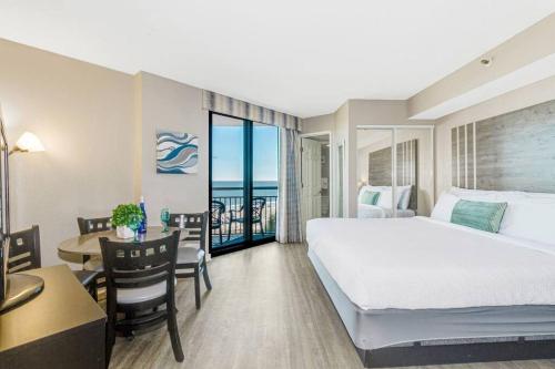 a hotel room with a large bed and a table and a desk at High Tides & Good Vibes in our Oceanfront Studio! PG 326 in Myrtle Beach