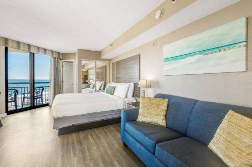 a bedroom with a bed and a blue couch at High Tides & Good Vibes in our Oceanfront Studio! PG 326 in Myrtle Beach