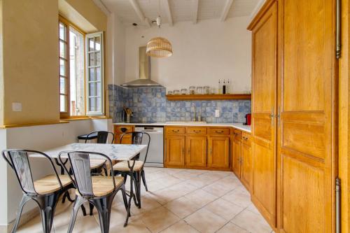 une cuisine avec des armoires en bois et une table et des chaises dans l'établissement La Maison du Forgeron - Maison au calme de 110 m2, à Marsac