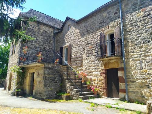 - un vieux bâtiment en pierre avec des escaliers et un balcon dans l'établissement Gite de canilhac, à Canilhac