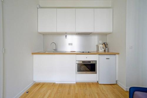 une cuisine avec des armoires blanches et un évier dans l'établissement Grand Studio 2 pers République Bastille Paris 3, à Paris