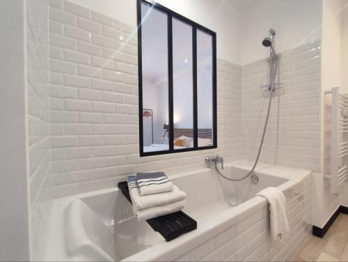 a white bathroom with a tub and a mirror at La Chambre Jaune - Chambre avec salle de bain in Argenton-sur-Creuse