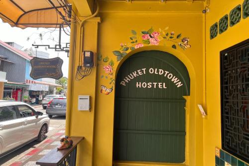 a yellow building with a green door with the words guest obligation hospital at Phuket Old Town Hostel in Phuket Town