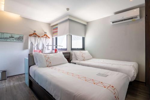 two beds in a room with a window at Vib Best Western Sanam Pao in Bangkok