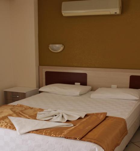 two beds with white sheets and a towel on them at Arya Otel in Marmaris