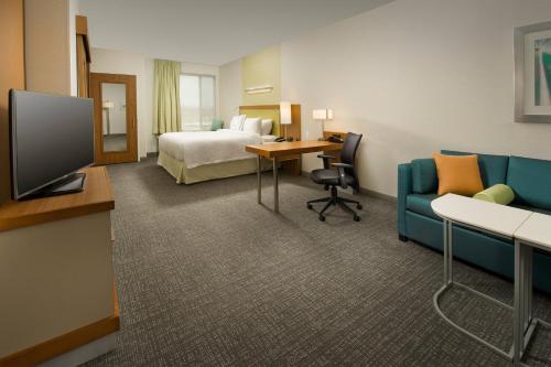 a hotel room with a bed and a tv and a couch at SpringHill Suites by Marriott Bridgeport Clarksburg in Bridgeport