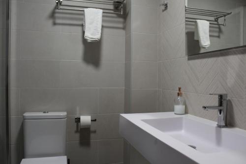 a white bathroom with a sink and a toilet at Hotel Rego Foz in Foz