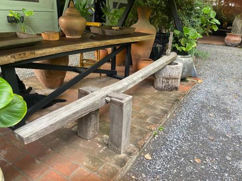 a wooden bench sitting next to a table with vases at Mintys Folly 2 in Ban Man