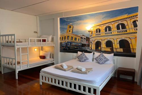 a bedroom with a bed and a painting of a building at Phuket Old Town Hostel in Phuket Town