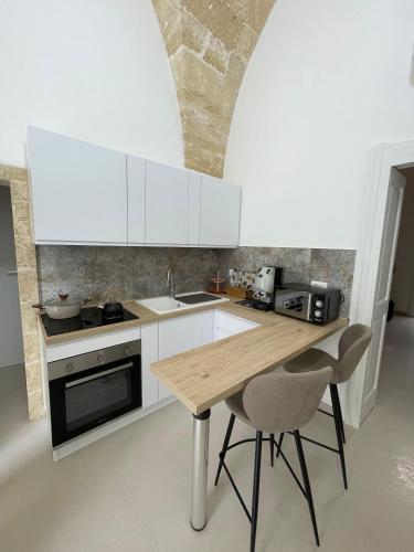 a kitchen with white cabinets and a wooden table at Casina Carducci Apartment in Nardò