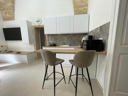a kitchen with white cabinets and two chairs at a counter at Casina Carducci Apartment in Nardò