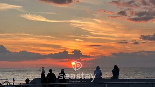 a group of people sitting on the beach watching the sunset at Aurora Spa Seaview Penthouse Ramsgate in Kent