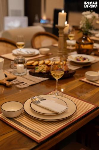 a table with plates and a glass of wine on it at Middle Earth by Vieda - Part of StayVista with Pool in Karjat