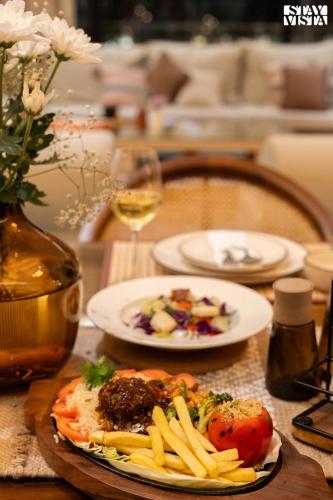 a table with plates of food and a glass of wine at Middle Earth by Vieda - Part of StayVista with Pool in Karjat