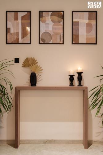 a table with two candles on it against a wall with pictures at Middle Earth by Vieda - Part of StayVista with Pool in Karjat