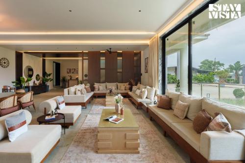 a large living room with white couches and tables at Middle Earth by Vieda - Part of StayVista with Pool in Karjat