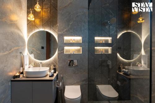 a bathroom with two sinks and two mirrors at Middle Earth by Vieda - Part of StayVista with Pool in Karjat