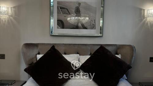 a picture on the wall above a bed with black pillows at Aurora Spa Seaview Penthouse Ramsgate in Kent