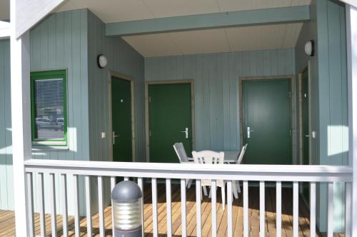 eine Veranda mit grünen Wänden, einem weißen Tisch und Stühlen in der Unterkunft Gästedorf Waldheimat in Langenwang