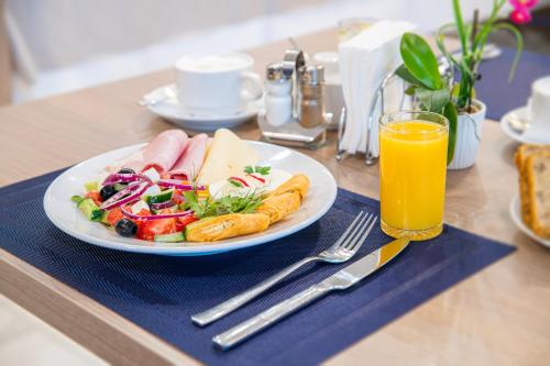 uma mesa com um prato de comida e um copo de sumo de laranja em Hotel Urbi em Gdańsk