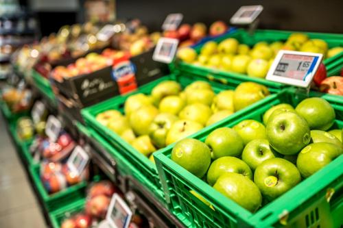a produce section of a grocery store with green baskets of apples at Alpine Chalet Sauter in San Vigilio Di Marebbe