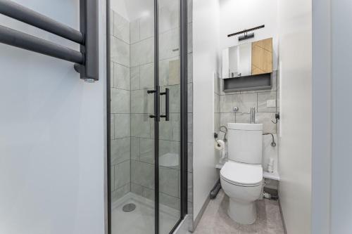 a bathroom with a toilet and a glass shower door at Premium Żeglarska 24 in Toruń