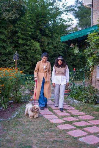 two women walking a dog on a path at Alaya Stays 3 BHK Pet-friendly with Garden - Chalet Vie Villa in Dharampur