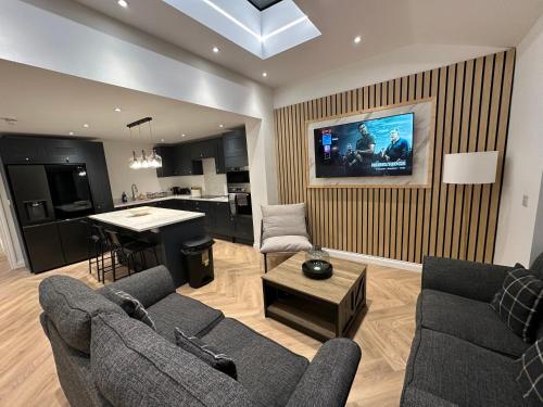 a living room with a couch and a tv on a wall at 6 bedroom house in Orpington in Farnborough