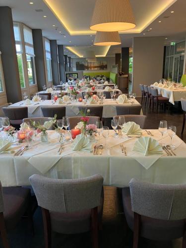 a large dining room with white tables and chairs at Hotel am Schlossberg in Herrenberg