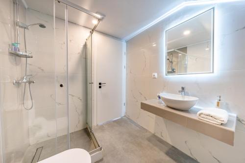 a bathroom with a sink and a glass shower at Starry Sky Luxury Apartment 2 in Lefkímmi
