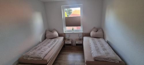 two beds in a small room with a window at FeWo mit 2 Schlafzimmern, WLAN und Waschtrockner in Weißenfels nahe Leuna, Leipzig in Weißenfels