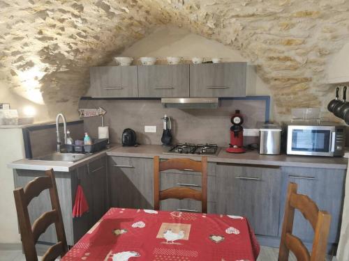 une cuisine avec une table et une cuisine avec un mur en pierre dans l'établissement Petite maison de village charmante et authentique, à Aniane