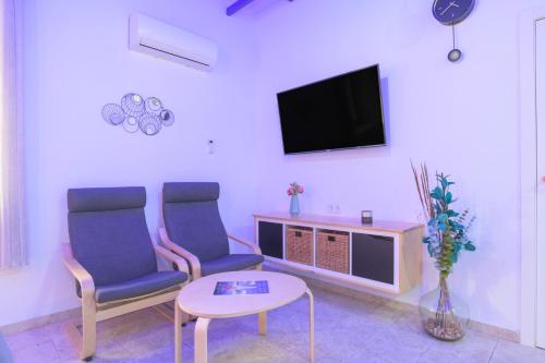 a living room with two chairs and a tv at Apartamentos Bellamar in Barbate