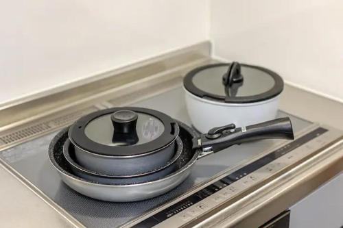 a stove top with two pans and a pot on it at 池袋駅まで徒歩15分 畳の家 in Tokyo