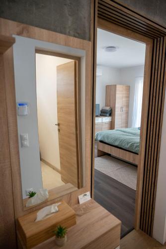 a mirror in front of a bedroom with a bed at Pipi és Papi vendégház in Kiskunlacháza