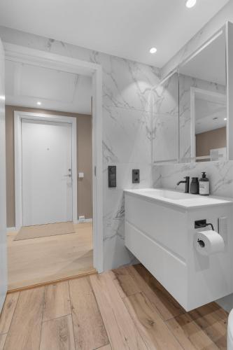 a white bathroom with a white sink and a door at Northstay - The Northview Retreat, Free Parking, Amazing Ocean Views in Tromsø