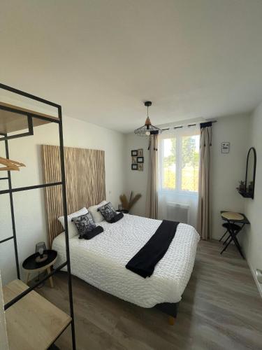une chambre avec un lit avec des draps blancs et des oreillers noirs dans l'établissement T4 Lumineux proche Centre Ville Narbonne & Des Grands Buffets, à Narbonne