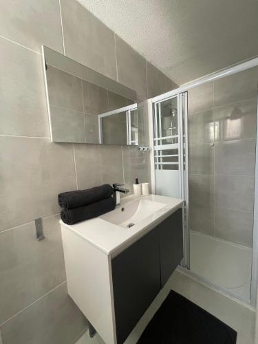 une salle de bain avec un lavabo blanc et une douche dans l'établissement T4 Lumineux proche Centre Ville Narbonne & Des Grands Buffets, à Narbonne