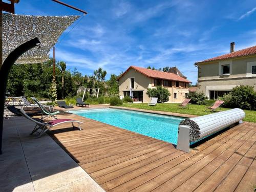 une piscine avec une terrasse en bois à côté d'une maison dans l'établissement Gîte campagne famille 15 pers Piscine chauffée Jeux enfants Pétanque, à Saint-Sauvy