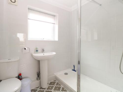 een witte badkamer met een wastafel en een douche bij 102 Waterside Park in Lowestoft
