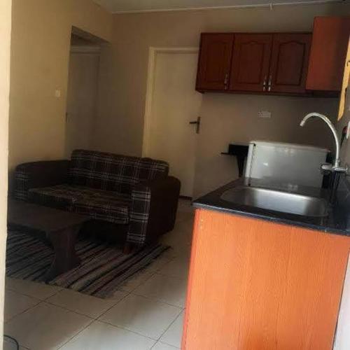 a living room with a couch and a kitchen at Tgs Homestay Nest in Kampala