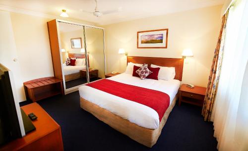 a hotel room with a large bed and a mirror at Governors Lodge Resort Hotel in Burnt Pine