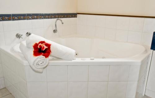 a white bath tub with a towel and a red flower on it at Governors Lodge Resort Hotel in Burnt Pine