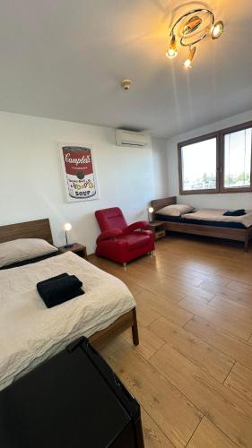a bedroom with two beds and a red chair at Hotel Muza in Košice