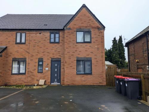 a brick house with two windows and two trash cans at Tempting Telford 4 bed house in Telford