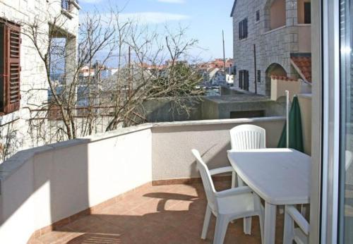 a balcony with a white table and chairs on a building at Apartments Paulina in Postira