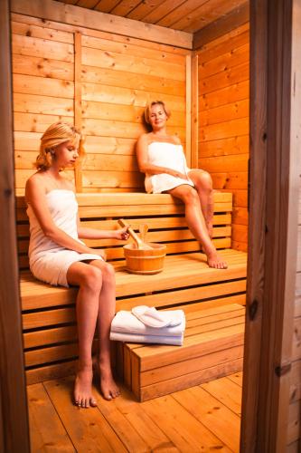 two women are sitting in a sauna at VSG Resort - Apartments 200m from Beach, Pool, Sauna & Jacuzzi in Klimno